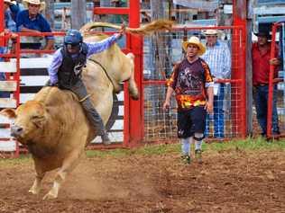 Bull rider Lane Mellers competes at Gayndah earlier this year as his uncle Brian King (right) watches on. Picture: Felicity Ripper