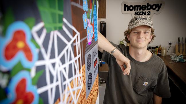 Tom Oswald at his North Terrace cafe, Homeboy, with painting by local artist Adam Tarif. Picture: Emma Brasier