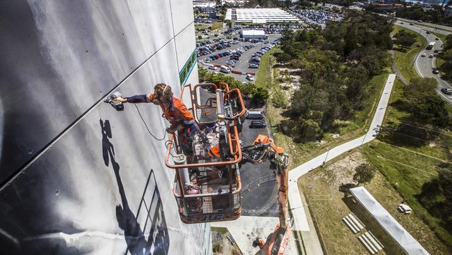 World-renowned large/scale artist Guido van Helten painting the 10-storey building at Southern Cross University Gold Coast campus. Picture: Nigel Hallett.