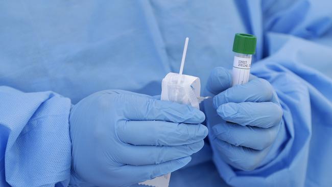 FILE - In this March 20, 2020, file photo, a health care worker prepares to collect a sample to test for COVID-19 at a drive-thru testing site in Miami. Thieves steal surgical masks. A clinic sells fake COVID-19 tests. Hate groups encourage sick members to infect law enforcement officers. Imposters pose as public health officials. As the coronavirus pandemic spreads across the globe so too do the crimes related to it. (AP Photo/Wilfredo Lee, File)