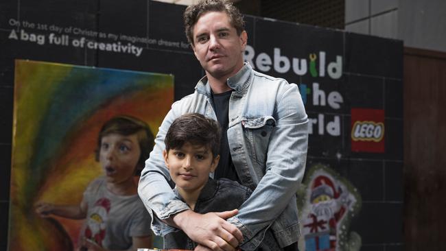 Artist Vincent Fantauzzo and son Luca at his mural (depicting younger son Valentino) for Lego reimagining Christmas in Knox Place, Melbourne.