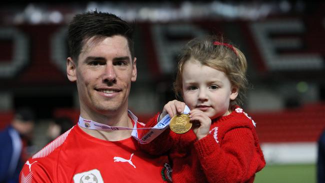 Campbelltown City’s Joel Allwright celebrates the 2019 grand NPL final 3-0 win over Comets with his daughter Arlo. (AAP/Emma Brasier)