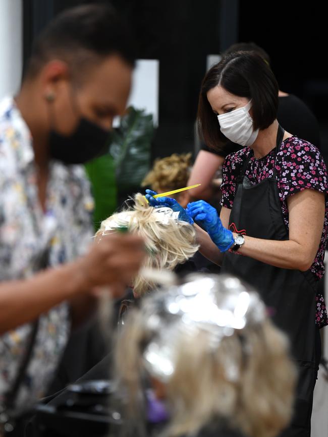 A hairdresser colours a customer's hair before the timing ban, then backflip. Picture: Dan Peled/AAPNG