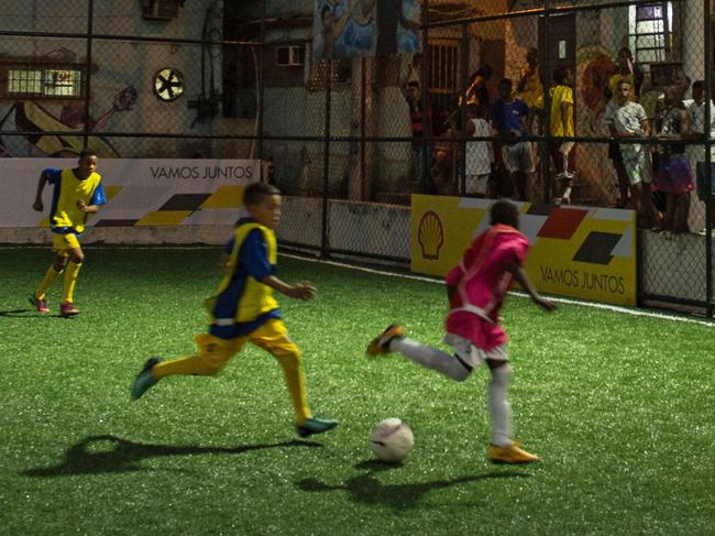 Children play football after the inauguration ceremony of the new technology pitch installed at Mineira favela in Rio de Janeiro, Brazil, on September 10, 2014. 200 self energy supplied “Pavegen” panels, invented by British Laurence Kemball-Cook, were installed underground to capture kinetic energy created by the movement of the football players. The energy is stored and combined with solar panels' energy to illuminate the pitch during the night. The new technology pitch was created by oil giant Royal Dutch Shell. AFP PHOTO / YASUYOSHI CHIBA