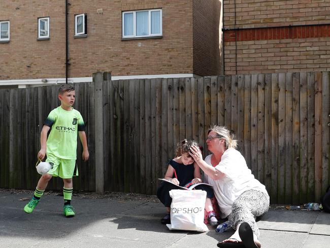 Thea West with a relative near to the fire-ravaged block of flats. Picture: AFP