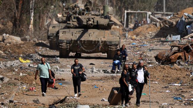 Palestinians fleeing the north through the Salaheddine Road, in the Zeitoun district on the southern outskirts of Gaza City, walk past Israeli army tanks on November 24, following a four-day ceasefire. Picture: Mahmud Hams/AFP
