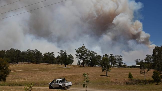 A car drives as a bushfire burns out of control in Hillville road near Taree, 350km north of Sydney. Picture: Peter Parks/AFP