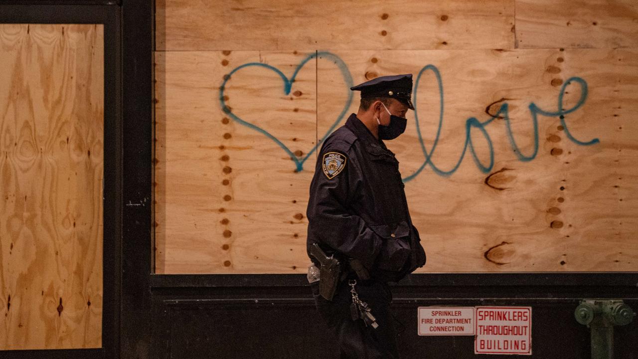 A police officer walks by graffiti on a boarded-up business as protesters take to the streets calling for every vote to be counted as the results of the election remain uncertain. Picture: David Dee Delgado/Getty Images/AFP.