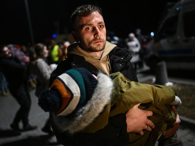 A man holds a sleeping baby after arriving by bus to a supermarket parking lot from the Polish-Ukrainian border crossing in Przemysl, Poland. Picture: Getty Images