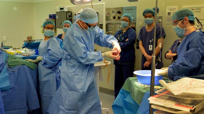 Surgeon Tim Furlong carries the kidney from the patient to a table to prepare it for transport. Picture: Jay Town