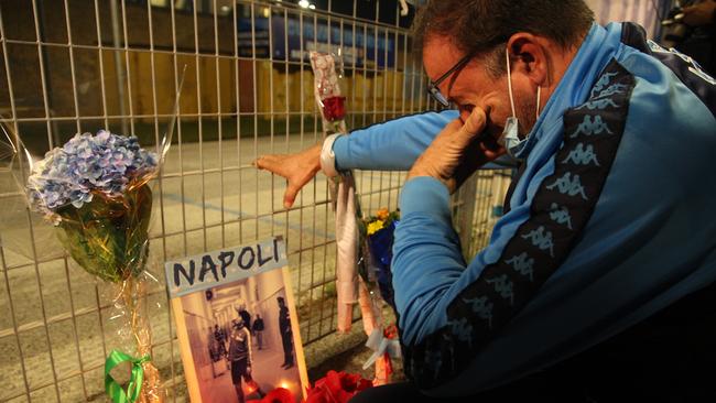 A man cries in front of a makeshift shrine set up at the main entrance of the San Paolo stadium in Naples. Picture: AFP