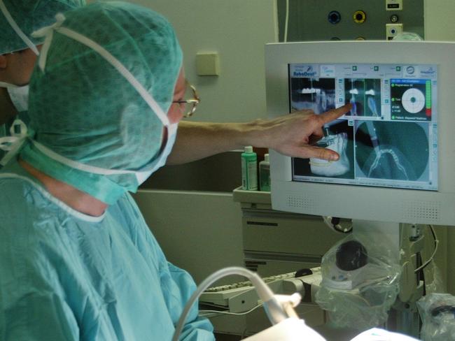 12/01/2005: A dental surgeon looks at the screen of the new "Navigated Control" system during an operation at the Virchow-Klinikum clinic in Berlin.  This system, combining computer technology with surgical operations via a screen, automatically stops surgical tools like drills, milling machines and saws, if a surgeon leaves a programmed path inside the human body.  (AP Photo/ Jan Bauer)