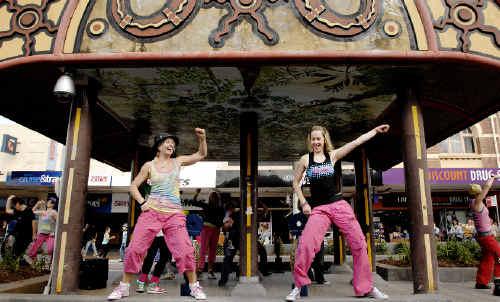 Dance on: Zumba Instructors Tessa Brauer (left), Josie Robertson and other flash mob dancers from Summit Sports and Fitness Centre stopped traffic in the middle of Woodlark Street yesterday in an effort to promote healthy lifestyle. Picture: Jay Cronan