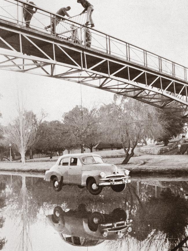 University students check out the FJ Holden motor car hanging from the Adelaide University footbridge, as part of an orientation week stunt. Picture: A student publication from 1971.