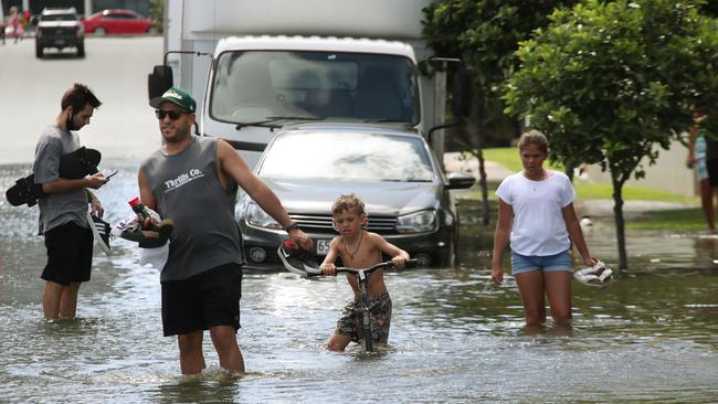 Flooding from the King tide at Budds Beach at Surfers Paradise was made worse by the approaching storm system. People wading through the floodwaters. Picture Glenn Hampson