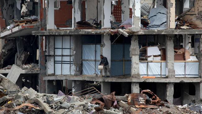 TOPSHOT - A Palestinian man clears debris on the first floor of a destroyed building in Jabalia in the northern Gaza Strip on February 5, 2025, during a truce in the war between Israel and Hamas. In hunger-stricken makeshift shelters set up in former schools, bombed-out houses and cemeteries across the Gaza Strip, devastated by 15 months of war between Hamas and Israel, hundreds of thousands lack even plastic sheeting to protect from winter rains and biting winds, aid workers say. (Photo by Bashar TALEB / AFP)