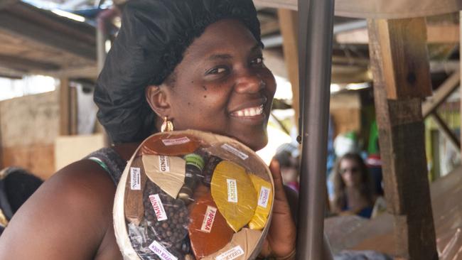 St. Georges, Grenada â€“ January 17, 2015: Smiling female market stall trader, looking into the camera, offers a pack of mixed local spices at the famous Saturday morning market in St. Georges, market square, Island of Grenada. Photo: iStock