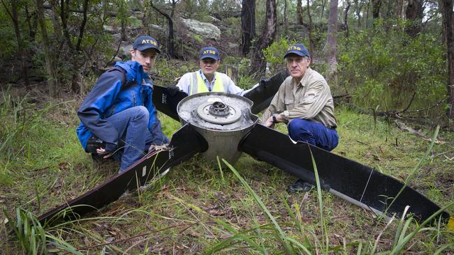 Australian Transport Safety Bureau investigators Aaron Holman (l to r), Greg Hood and Max Martin inspect the propeller that fell off a REX plane. Picture: Melvyn Knipe