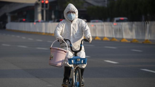 A resident wearing mask and suit against the coronavirus cycles in Wuhan in central China's Hubei province on April 12, 2020. Picture: Ng Han Guan