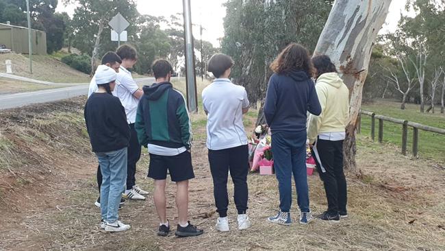 Friends look at the floral tributes at the scene of the fatal collision at Athelstone.