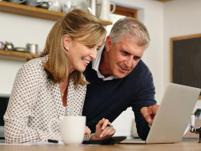 A senior couple planning their finance and paying bills while using a laptop at home. A mature man and woman going through paperwork and working online with a computer; superannuation money generic