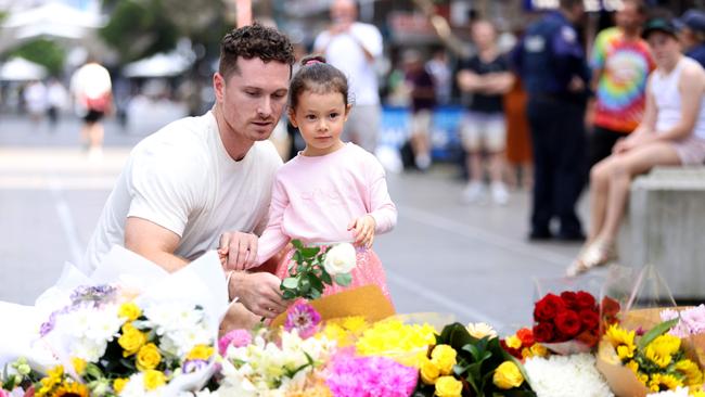 A young girl and her father leave flowers in Bondi Junction near where a stabbing incident killed multiple people on Saturday afternoon at the Westfield shopping centre. Picture: Damian Shaw