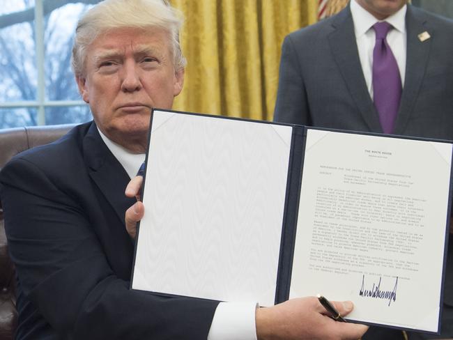 President Donald Trump holds up an executive order withdrawing the US from the Trans-Pacific Partnership with his distinctive spiky signature on the bottom. Picture: Saul Loeb/AFP.