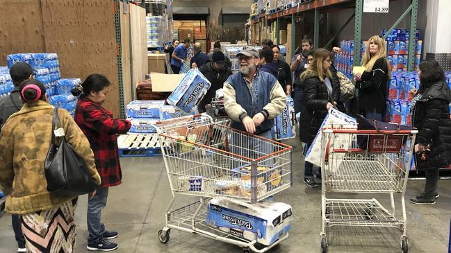 Shoppers wait their turns to pick up toilet paper in a Costco store. Picture: AP.