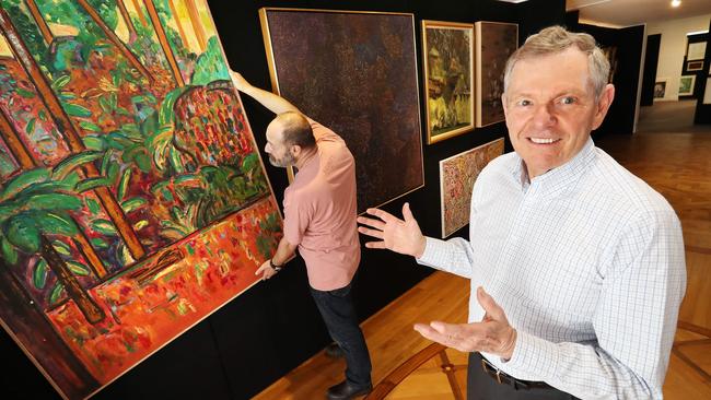 Philip Bacon oversees the hanging of a landscape by Jeffrey Makin up for grabs in the Philip Bacon Galleries Art Sale which opens to the public on Saturday. Photographer: Liam Kidston.