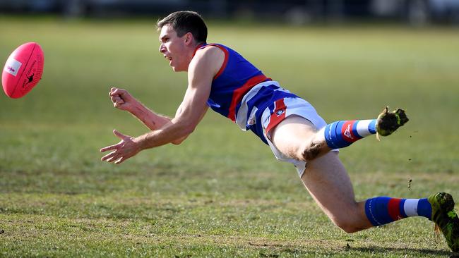 Gisborne’s playing coach Clinton Young gets a diving handpass away. Picture: Andy Brownbill