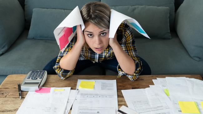 Portrait of worried and desperate young woman feeling stressed while working through finances. Sitting on the sofa making anxious gestures. In paying debts and bills and financial problems concept.