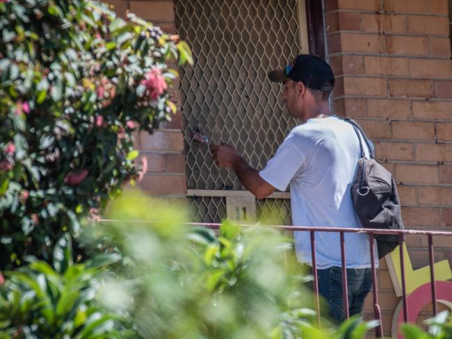 A man reaches out to grab an item from the cut-out hole in the door last month. Picture: Jason Edwards