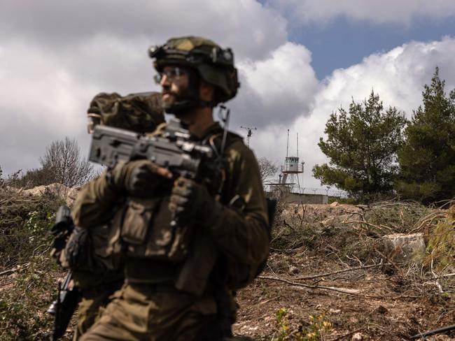 PHOTO TAKEN DURING A CONTROLLED EMBED TOUR WITH THE ISRAELI ARMY AND SUBSEQUENTLY EDITED UNDER MILITARY SUPERVISION -- This picture taken on October 13, 2024 during a controlled embed organised by the Israeli military, shows Israeli troops patrolling near a United Nations Interim Force In Lebanon (UNIFIL) base in the southern Lebanon's Naqoura region near the border. UN peacekeepers in Lebanon said Israeli tanks broke through a gate to enter a Blue Helmet position in Lebanon on October 13, after blocking their movement the previous day. (Photo by Menahem KAHANA / AFP)