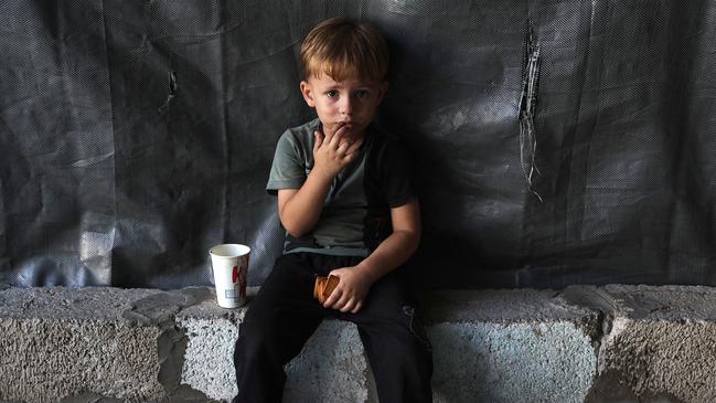 A child sits holding his biscuits at the Jabalia camp for displaced Palestinians in northern Gaza on August 29, 2024, amid the ongoing conflict between Israel and the militant Hamas group. (Photo by Omar AL-QATTAA / AFP)