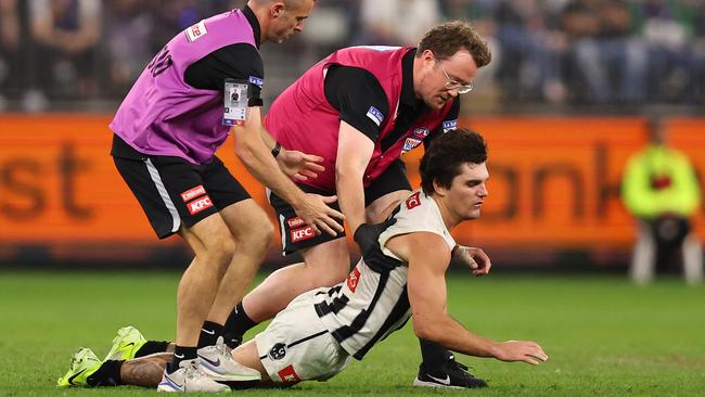 Lachie Schultz of the Magpies collapses in the hands of medical staff. Photo by Paul Kane/Getty Images.