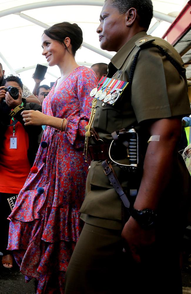 Security escorting the Duchess out of the crowded market.