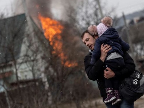 A man carrying a child flees the besieged city of Irpin. Picture: Reuters