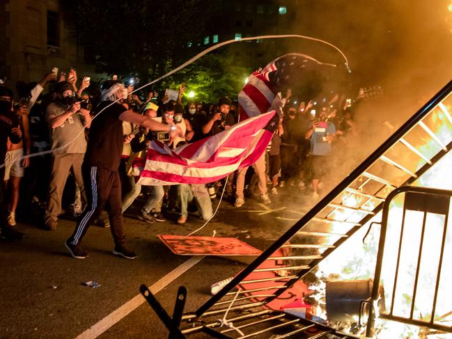 Protesters throw a US flag into a fire during a demonstration outside the White House over the death of George Floyd. Picture: AFP