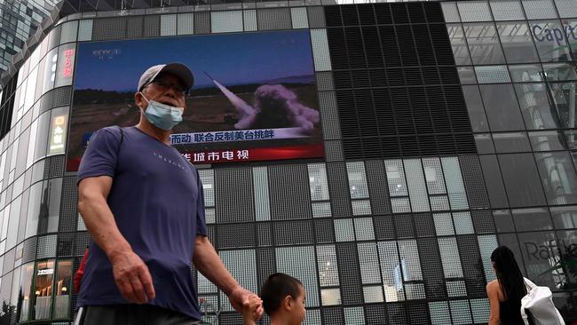 People walk in front of a large screen showing a news broadcast about China's military exercises encircling Taiwan, in Beijing on August 4. Picture: Noel Celis / AFP