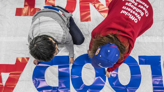 Western Bulldogs supporters work on their preliminary final banner. Picture: Jason Edwards