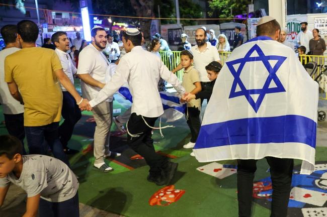 People dance and wave Israeli flags after hearing of the death of Hamas leader Yahya Sinwar, in the Israeli costal city of Netanya