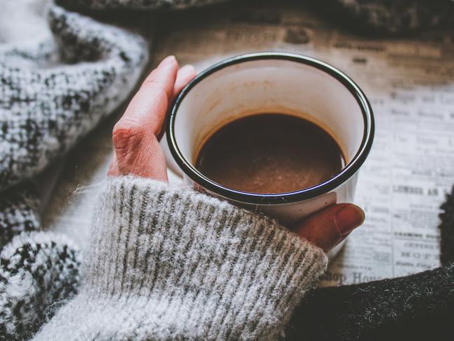 Woman wearing grey knit jumper holding hot drink