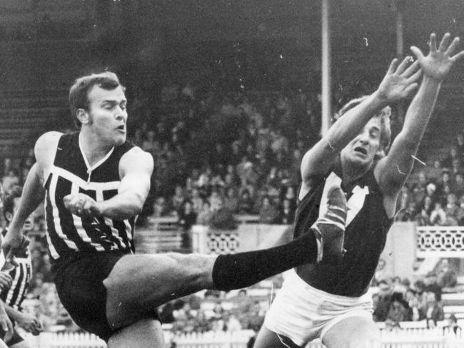 Footballer Peter Anderson trying to smother Eric Freeman's kick. SANFL football - Port Adelaide vs North Adelaide match Jul 1971.