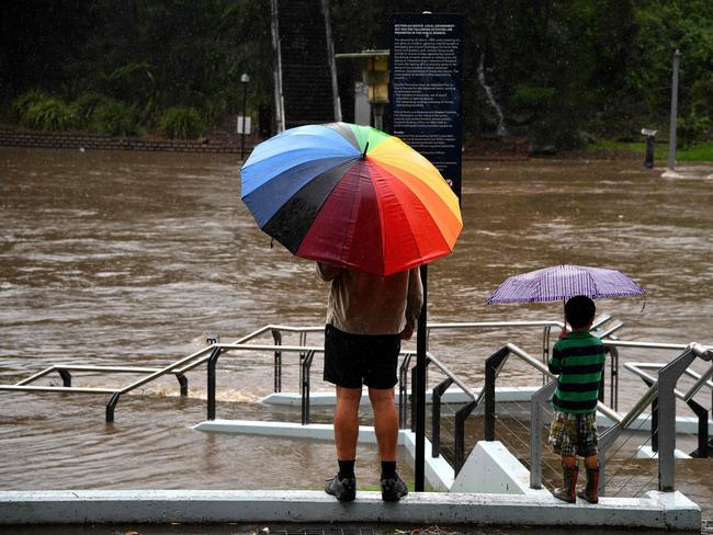 A family visit Ferry Wharf to watch the over flowing Parramatta river during heavy rain in Sydney on March 20, 2021, amid mass evacuations being ordered in low-lying areas along Australia's east coast as torrential rains caused potentially "life-threatening" floods across a region already soaked by an unusually wet summer. (Photo by Saeed KHAN / AFP)