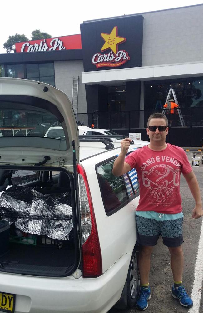 Burger fan Matt Elsey stands outside the Carl’s Jr Bateau Bay restaurant with his voucher giving him a year’s free burgers.