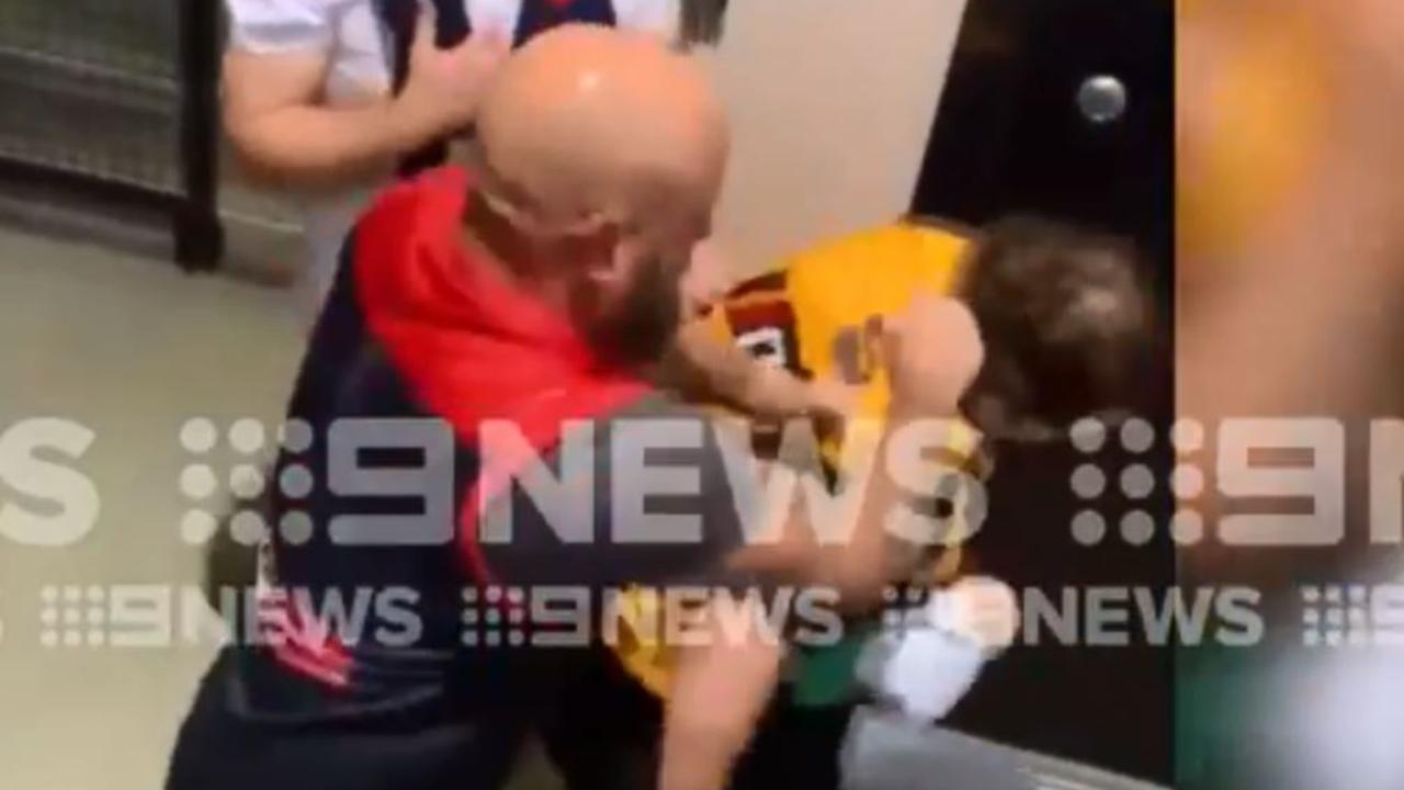 The Melbourne fan punches the Hawthorn fan.