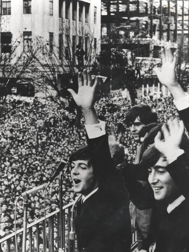 Paul McCartney (left), George Harrison and John Lennon of The Beatles wave to the massive crowd of fans gathered in Melbourne from the Southern Cross Hotel balcony, in June 1964. Picture: archive