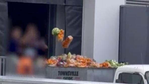 A shot of two Aldi workers filling a skip bin with produce that is to be disposed of. Picture: ABC news