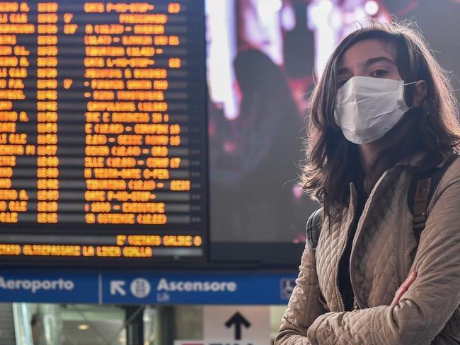 A woman wearing a respiratory mask waits by a timetable at the Termini railway station in Rome. Picture: AFP