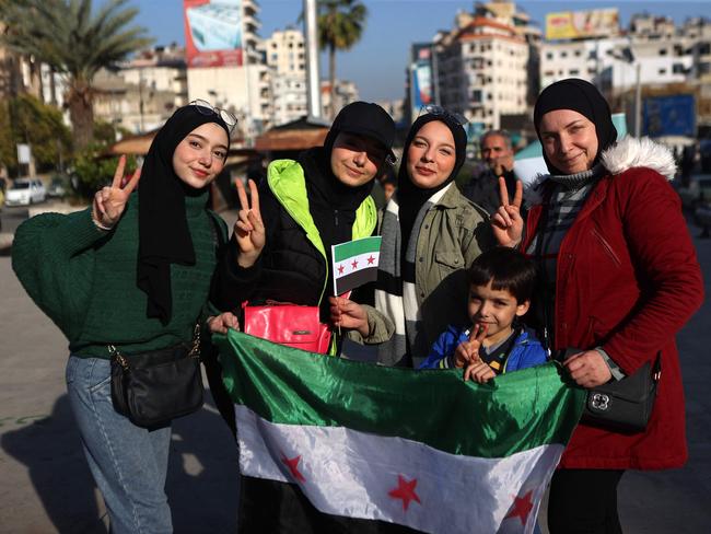 Syrians pose with the opposition flag at a street in the coastal Syrian city of Latakia on Tuesday. Picture: AFP